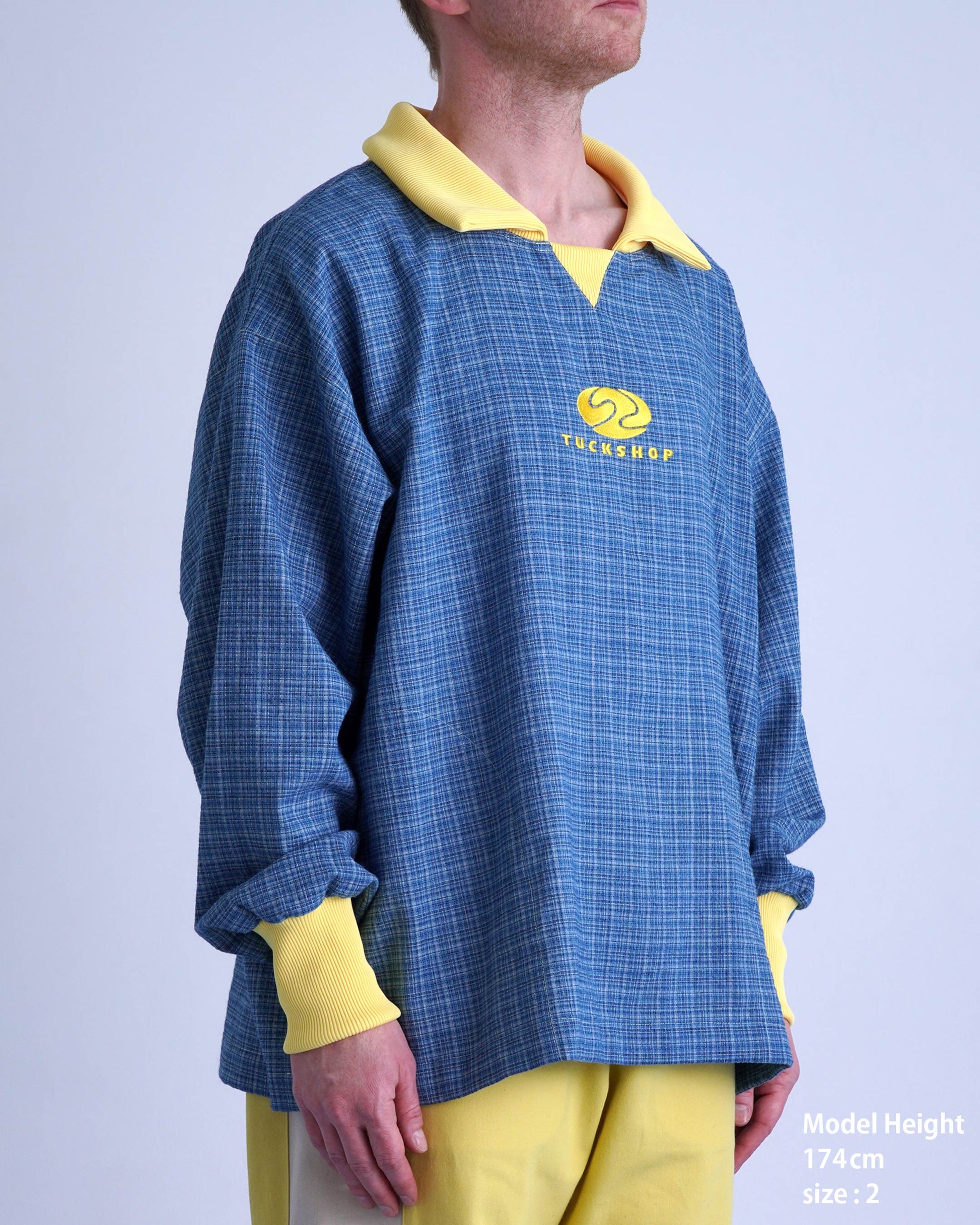 FOOTBALL POLO PULLOVERを着たモデル、ブルーとイエローのストライプ柄、落ち着いた雰囲気のプルオーバースタイル