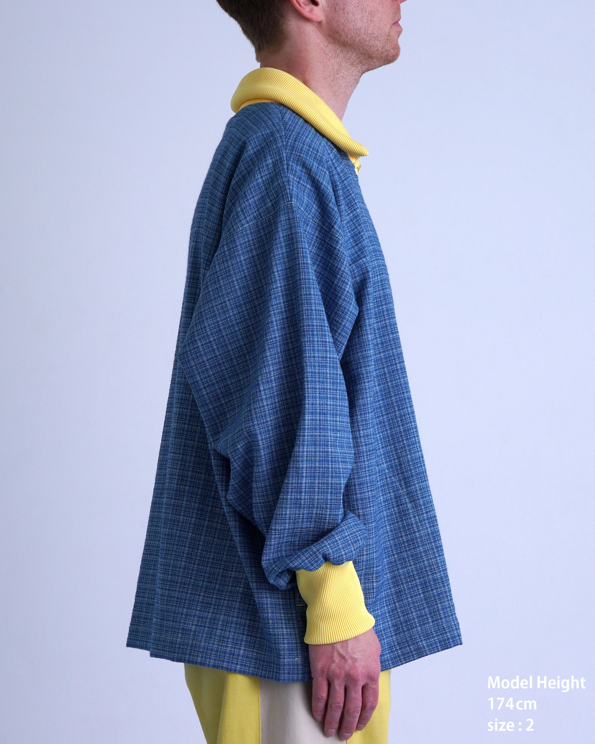 FOOTBALL POLO PULLOVERの横からのモデル写真。青いチェック柄、黄色い襟、ゆったりしたデザイン。