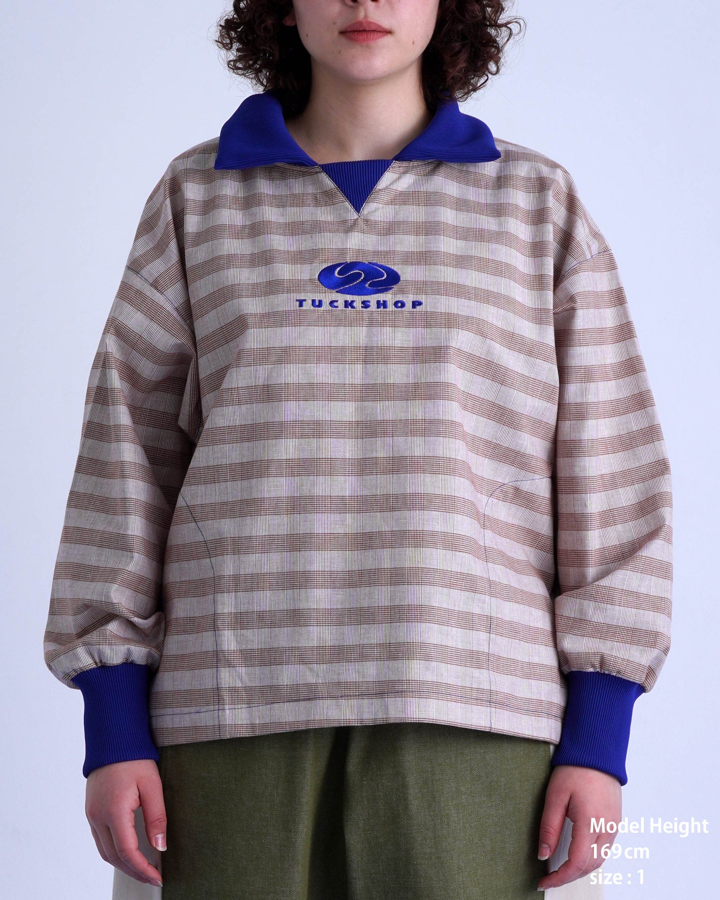 FOOTBALL POLO PULLOVERのストライププルオーバーを着たモデル。胸元のロゴと特徴的なカラーが目を引く。