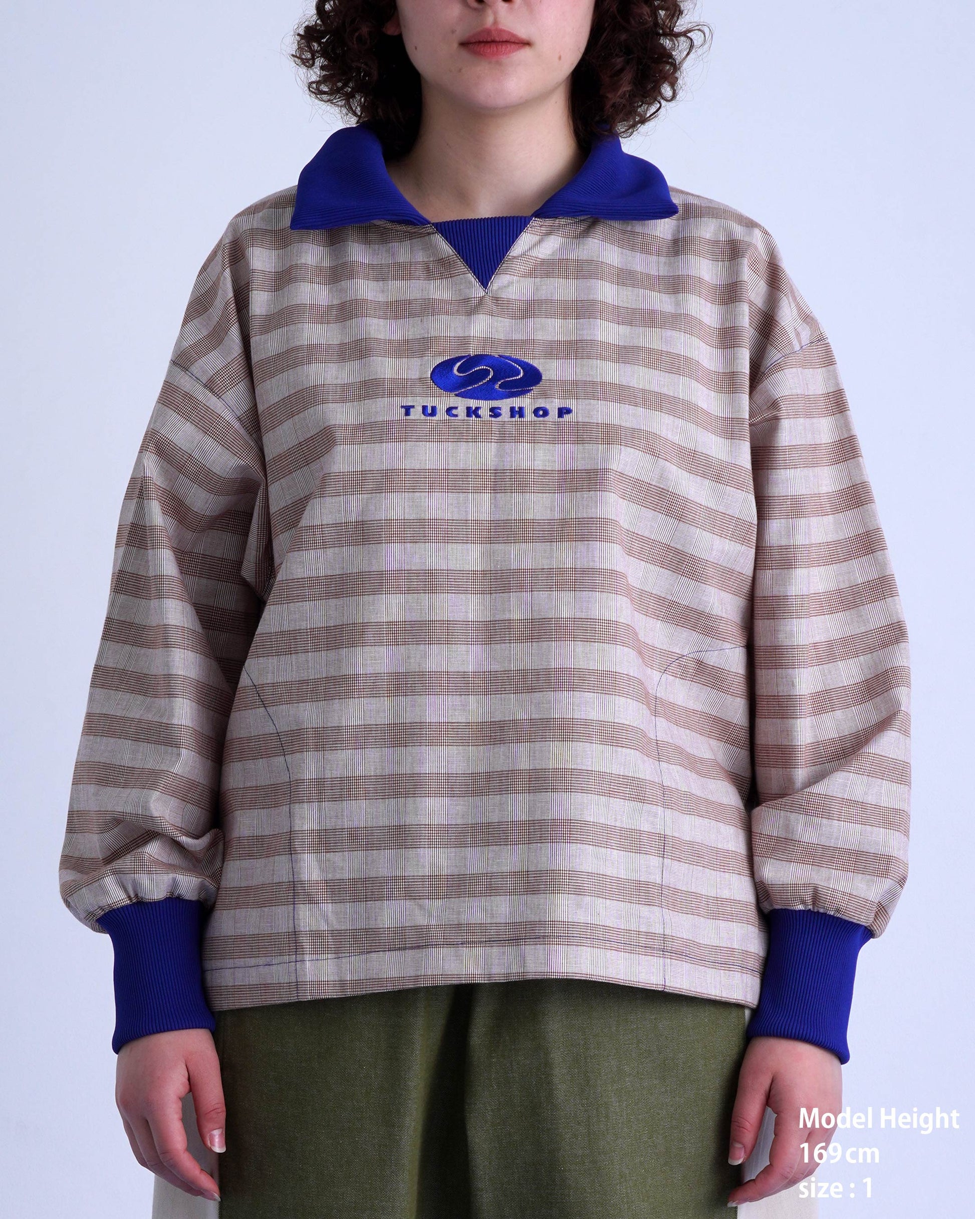 FOOTBALL POLO PULLOVERのストライププルオーバーを着たモデル。胸元のロゴと特徴的なカラーが目を引く。