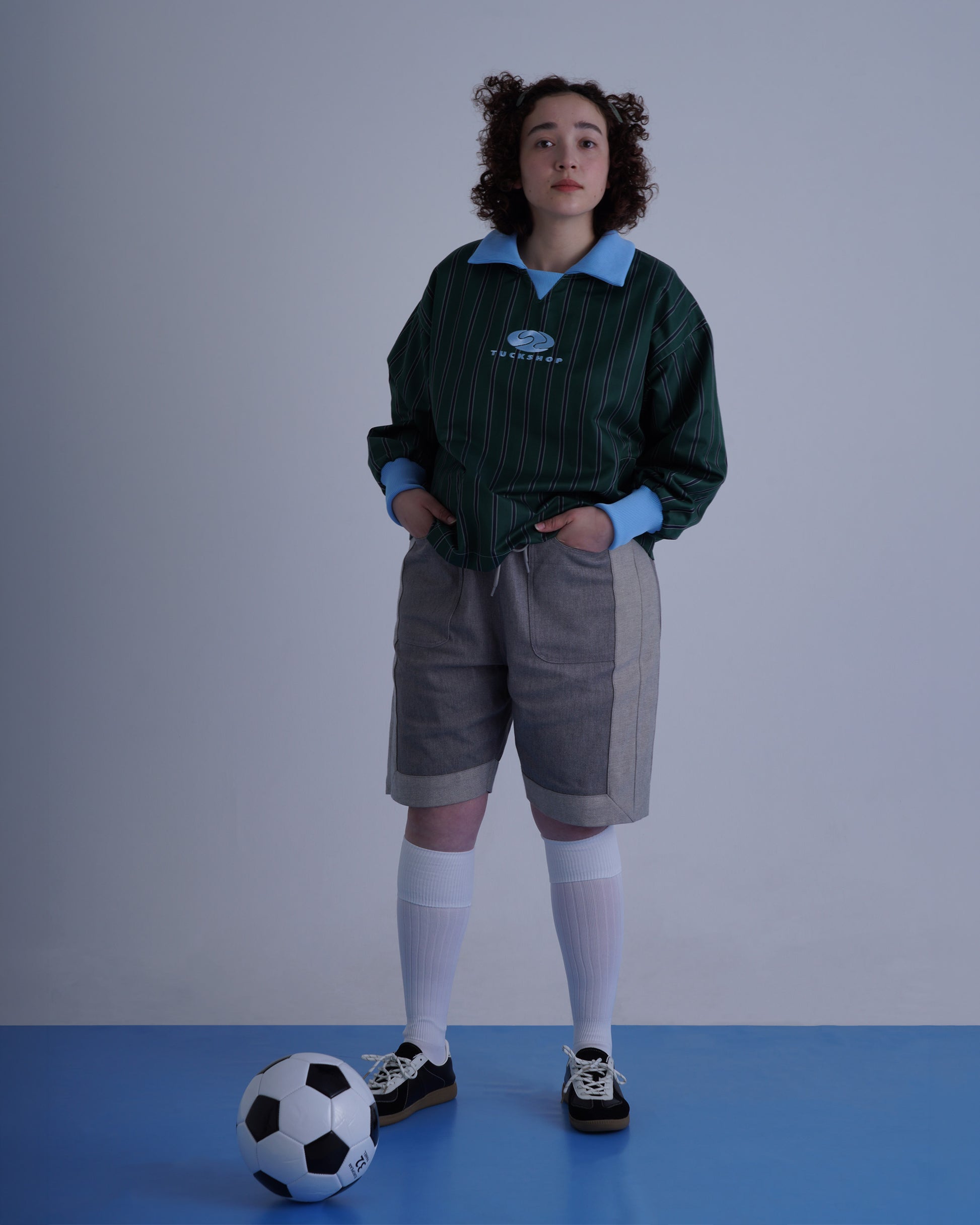 FOOTBALL POLO PULLOVERを着た女性がサッカーボールと共に立っている写真