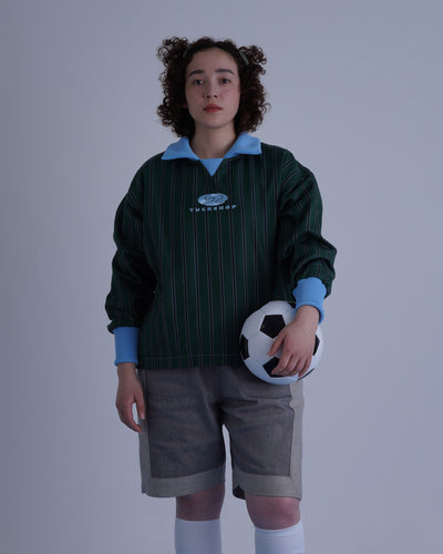 FOOTBALL POLO PULLOVERを着たモデルがサッカーボールを持っている写真。緑のストライプ柄のプルオーバー。