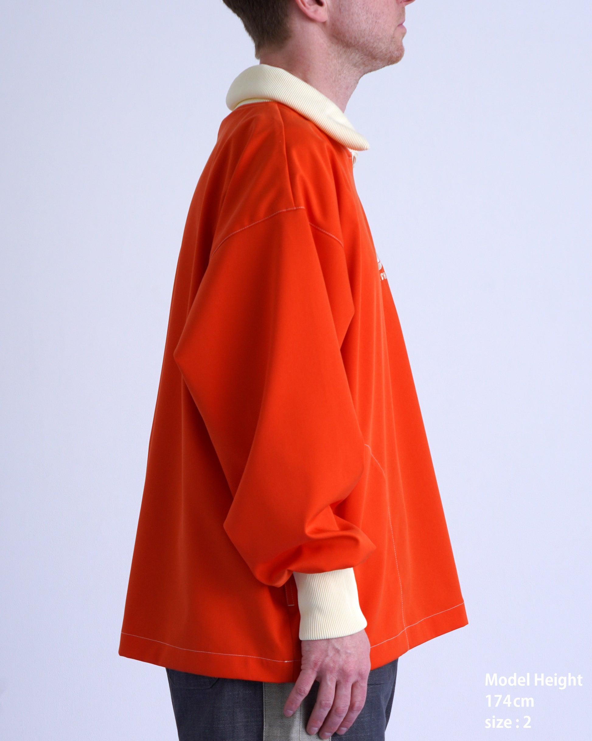 FOOTBALL POLO PULLOVERのオレンジ色プルオーバーを着用したモデルの横顔。