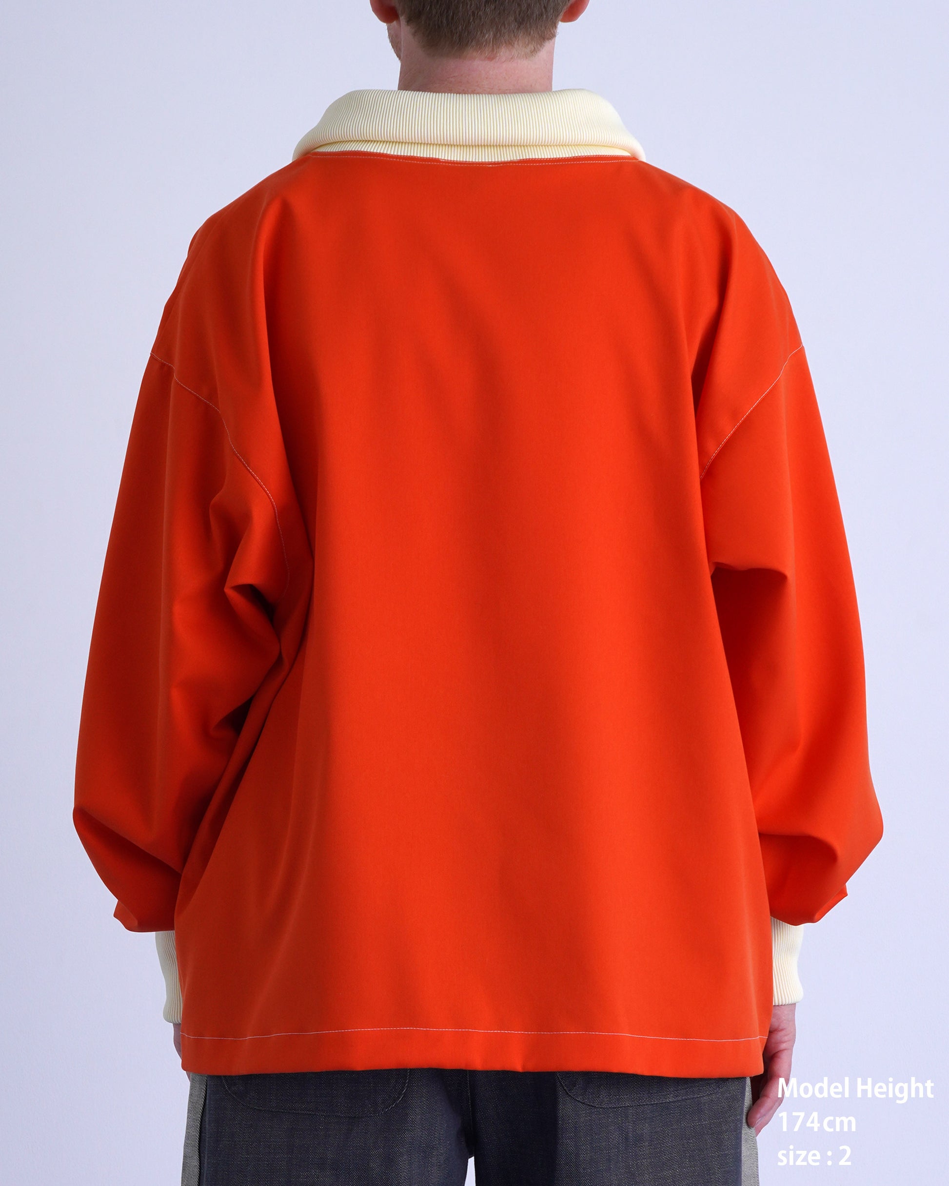 FOOTBALL POLO PULLOVERのオレンジ色プルオーバーの後ろ姿、モデル174cm、サイズ2。