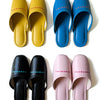 Colorful faux leather slippers in yellow, blue, black, and pink with logo print on instep.
