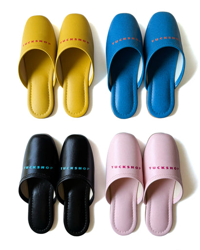 Colorful faux leather slippers in yellow, blue, black, and pink with logo print on instep.