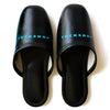 Black faux leather indoor slippers with logo print on instep, stylish and comfortable for home use.