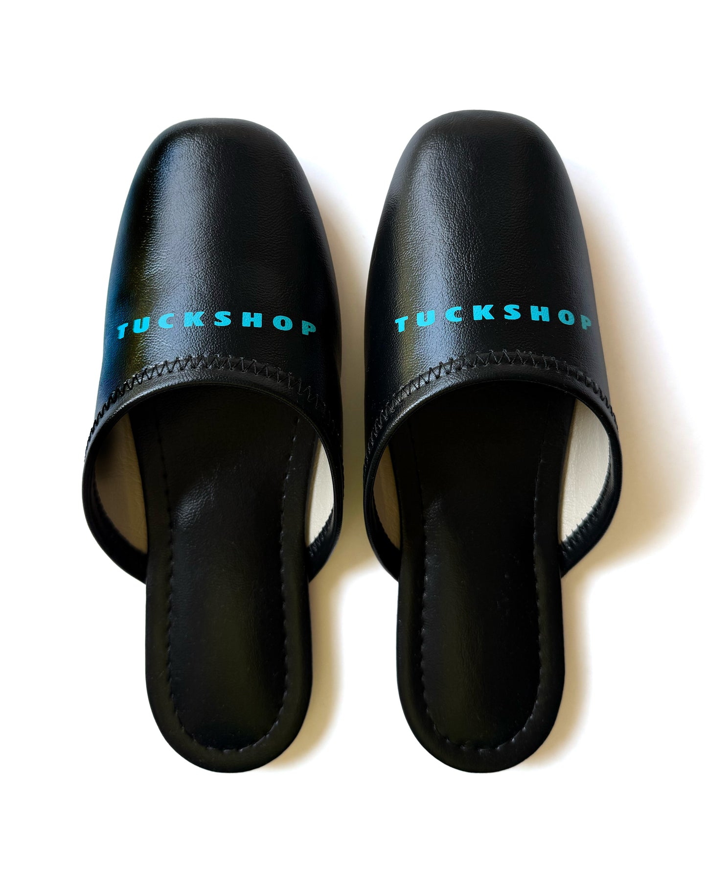 Black faux leather indoor slippers with logo print on instep, stylish and comfortable for home use.