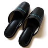 Black faux leather indoor slippers with logo print on instep, featuring a sleek design and comfortable fit.
