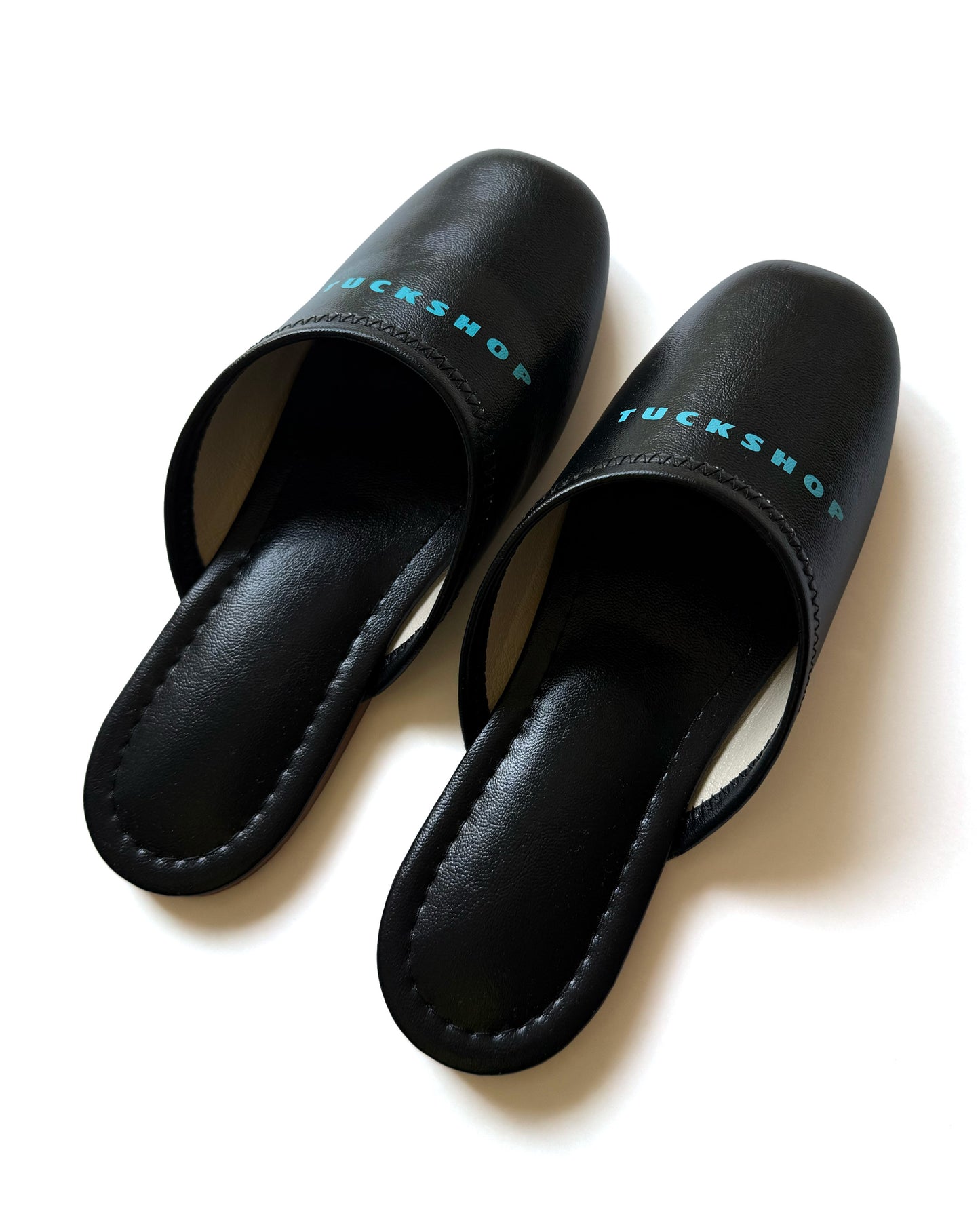 Black faux leather indoor slippers with logo print on instep, featuring a sleek design and comfortable fit.