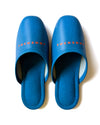 Blue faux leather indoor slippers with logo 'TUCKSHOP' printed on the instep.