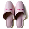 Pink faux leather slippers with TUCKSHOP logo on the instep, perfect for indoor use.