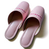 Pink faux leather slippers with 'TUCKSHOP' logo on instep, perfect for indoor use.