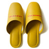 Yellow faux leather indoor slippers with logo print for comfortable home wear.