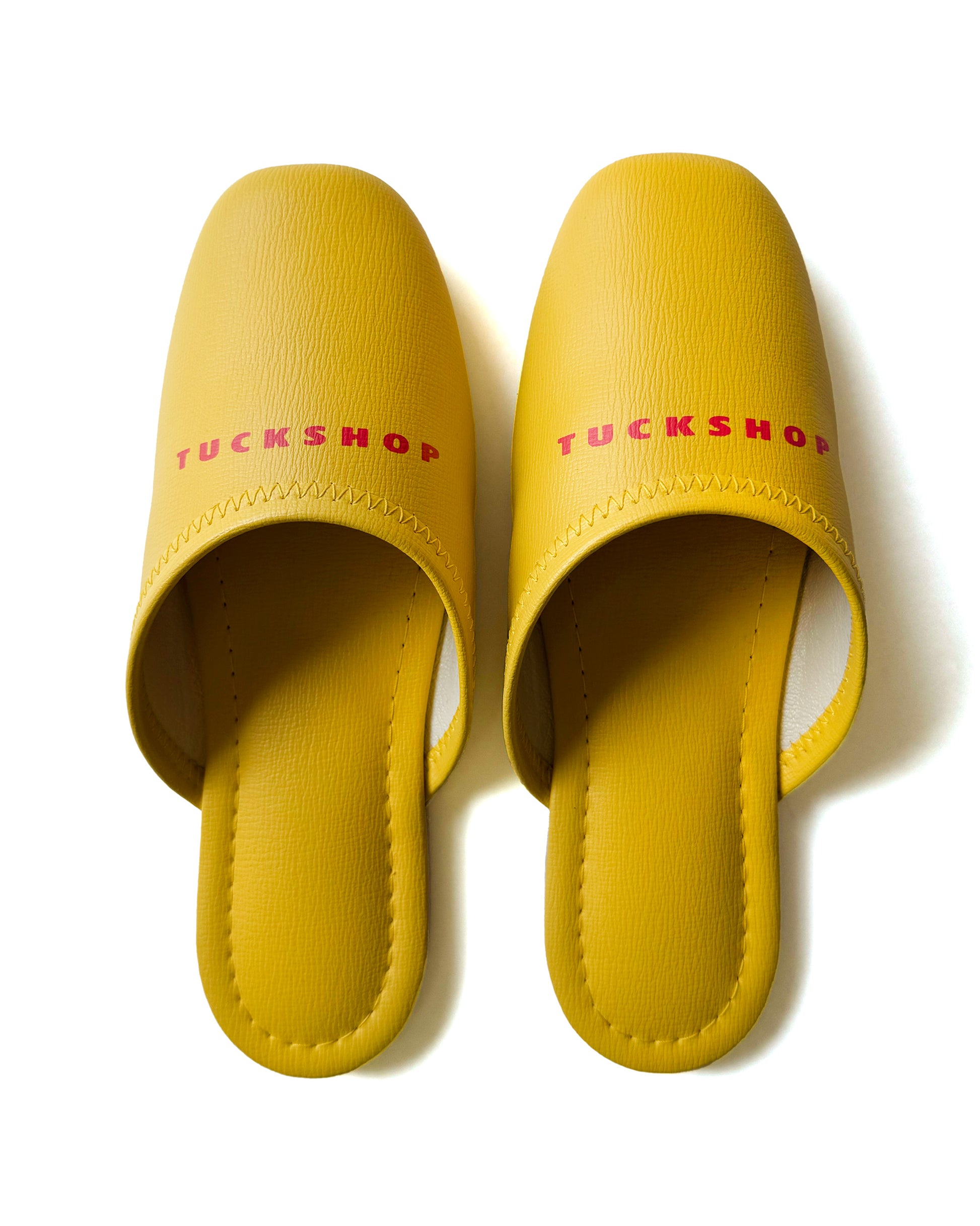 Yellow faux leather indoor slippers with logo print for comfortable home wear.