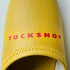 Yellow faux leather slipper with 'TUCKSHOP' logo printed in red on the instep.